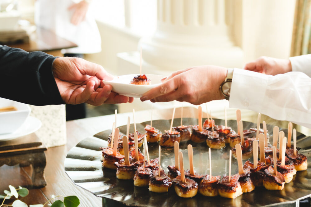 A person handing a plate of food to another person.