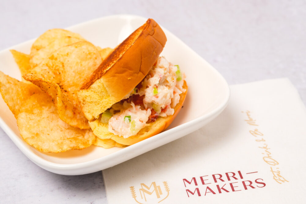 A sandwich with chips and a napkin on a white plate.