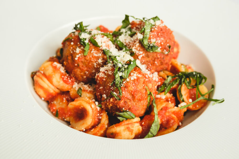 A white plate with meatballs and pasta on it.