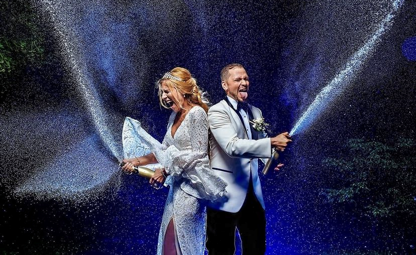 A bride and groom spraying champagne at their wedding.