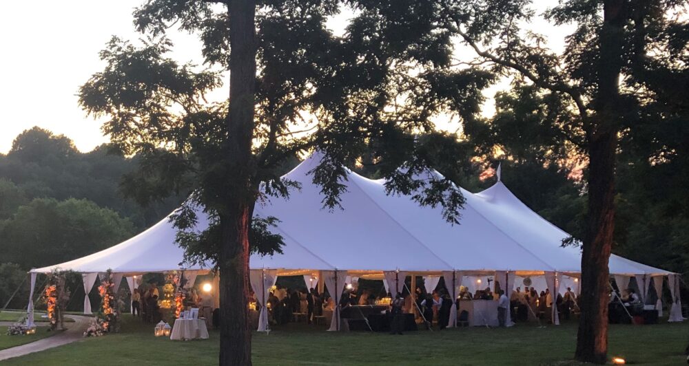 A white tent set up in a grassy area at dusk.