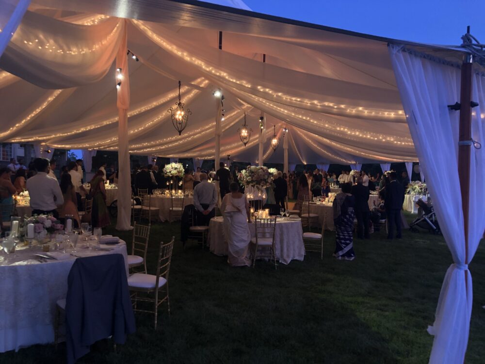 A wedding reception under a tent at dusk.