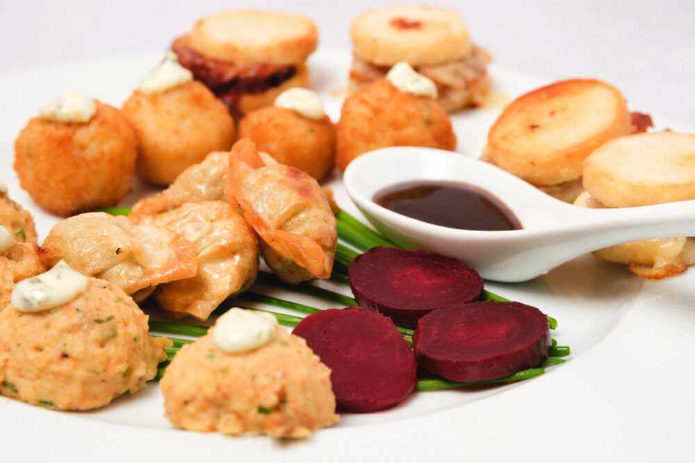 A plate with various appetizers and dips on it.