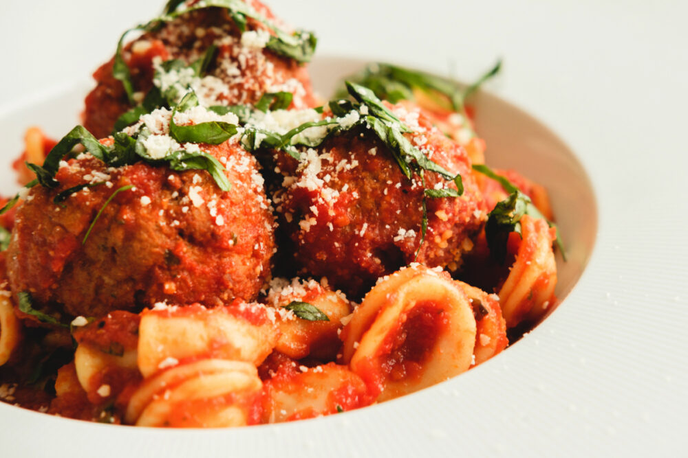 A white plate with meatballs and pasta.